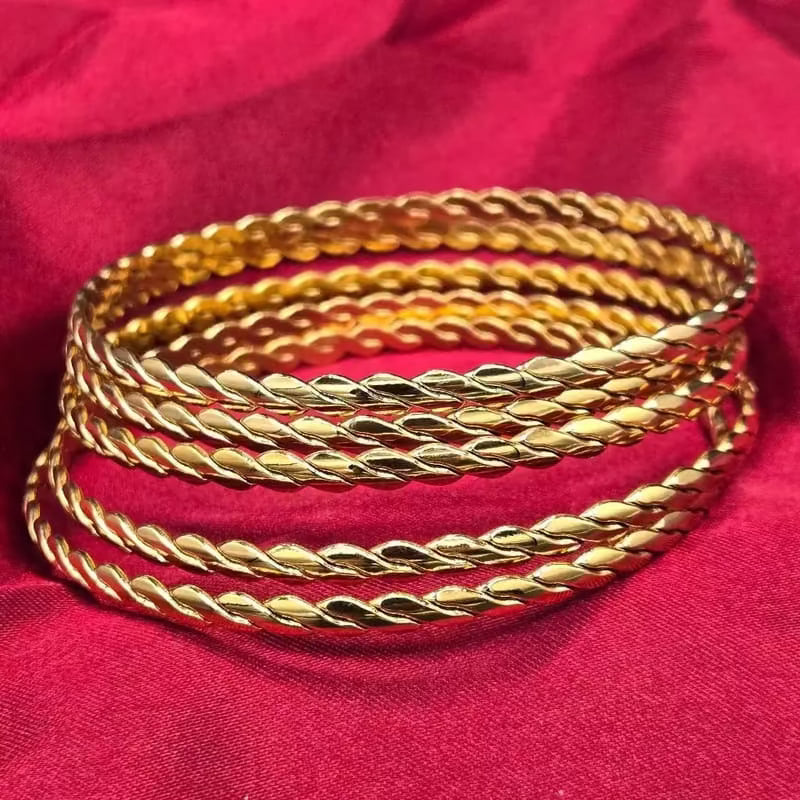 Twist Bangle in Gold finish on a red background