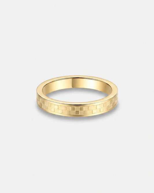 A slim yellow gold band ring with a textured geometric pattern on the outer surface, shown against a light gray background.