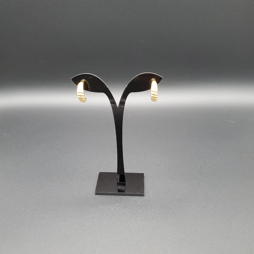 Black earring stand with gold earrings on a gray background