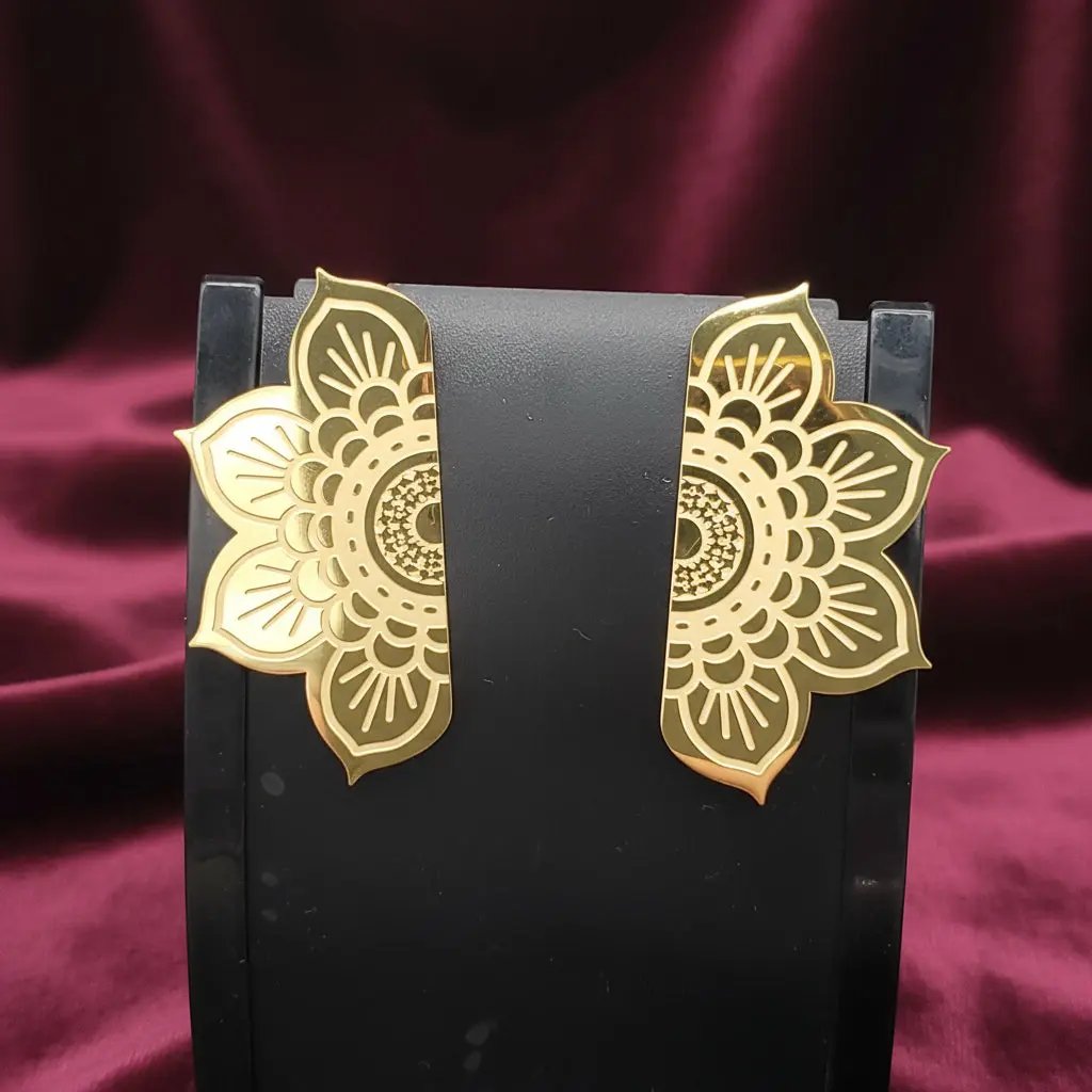 Gold floral earrings on a black stand against a red velvet background