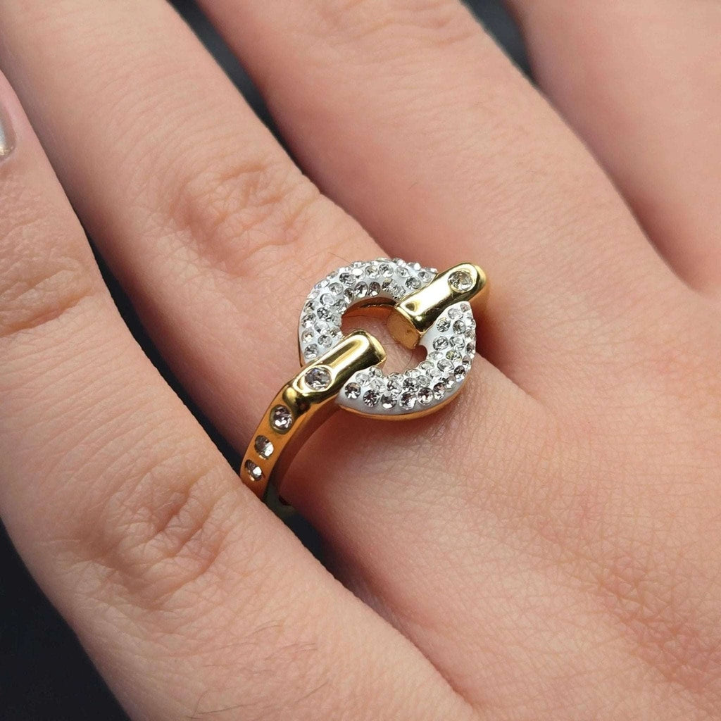 Gold ring with a diamond design on a person's finger
