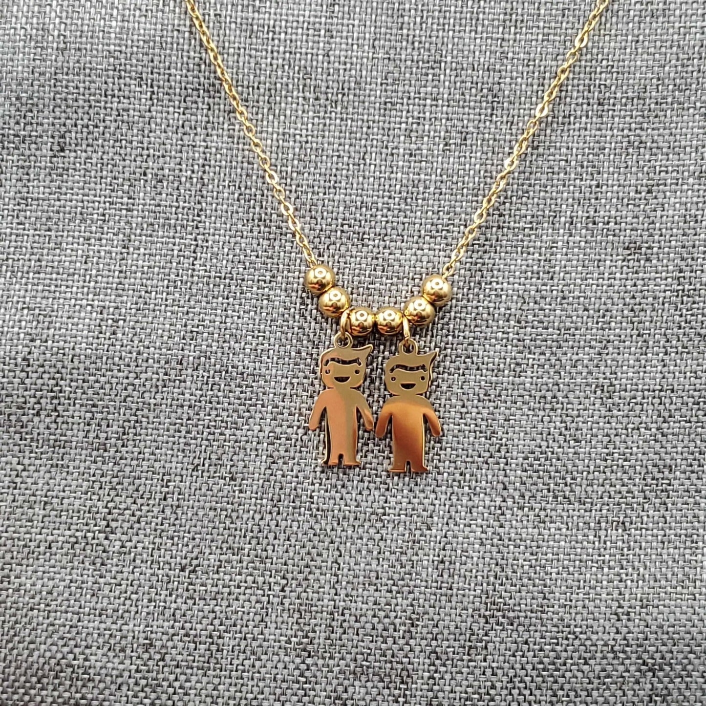Boy & Girl Necklace in Gold finish on a neutral background