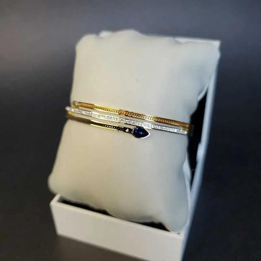 Classic Blue Teardrop Stone Bangle in Gold and Silver finish, with cubic zirconia stone on a neutral background