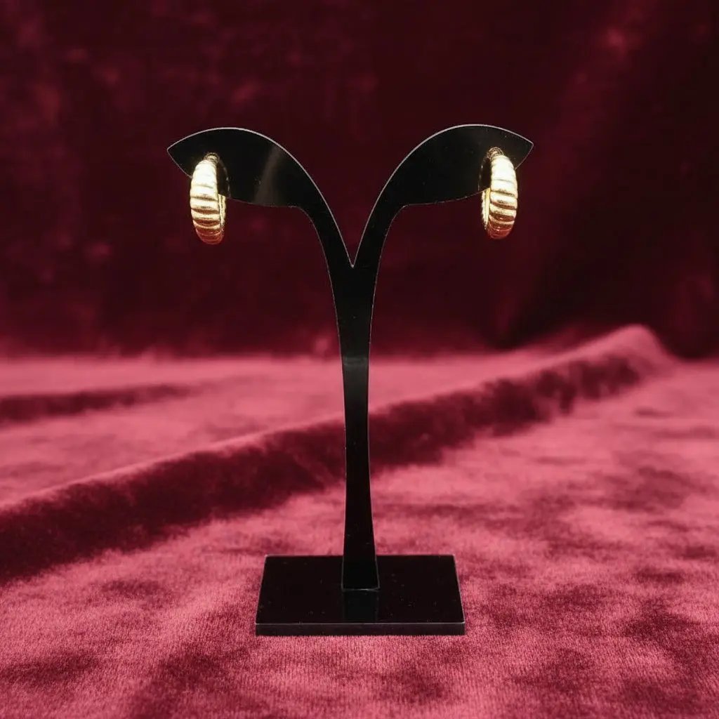 Gold hoop earrings on a black earring stand on a red velvet background