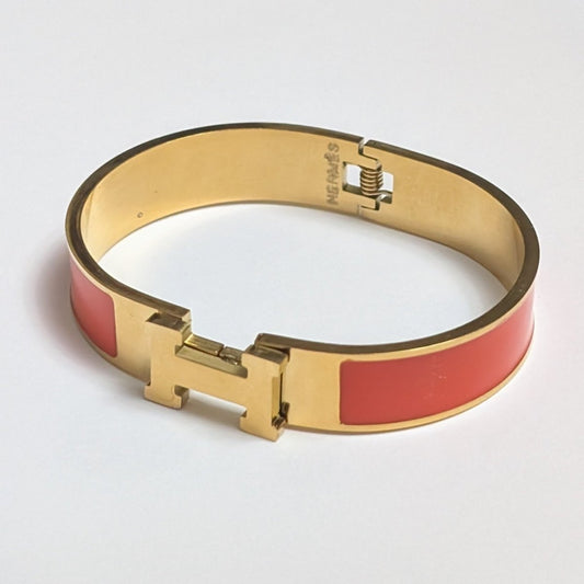 Gold bracelet with red accents on a light gray background