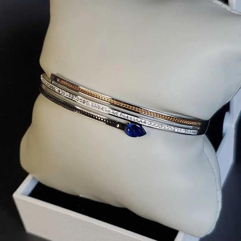 Modern Blue Teardrop Stone Bangle in Gold and Silver finish, with cubic zirconia stone on a neutral background