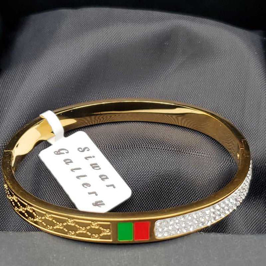 Modern Signature Bangle in Gold finish, with cubic zirconia stone on stones, green and red enamel, and engraved pattern