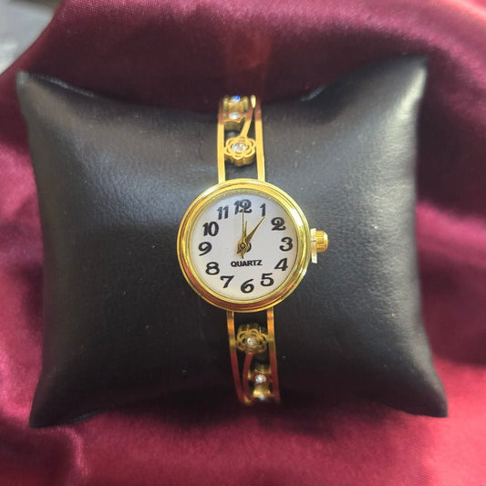 Gold watch on a black cushion with a blurred background