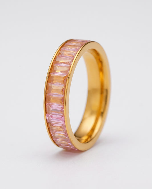 A gold eternity-style ring band with a channel setting of pink baguette-cut stones, shown on a plain white background.