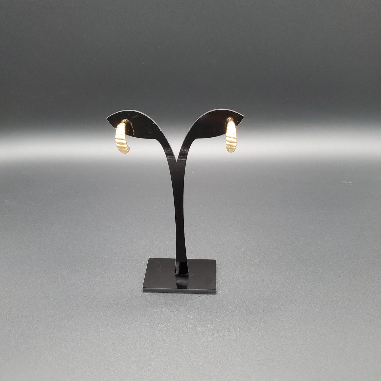 This image features a pair of sophisticated earrings, crafted from stainless steel with a glossy finish. The design is minimalist, with each earring extending from a sleek, black, rectangular base that supports a graceful, arched hook.