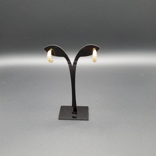 Black earring stand with gold earrings on a gray background