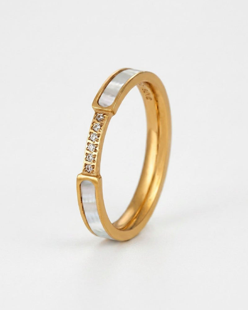 A gold band ring featuring a silver inlay with a row of small clear stones, photographed on a clean white background.