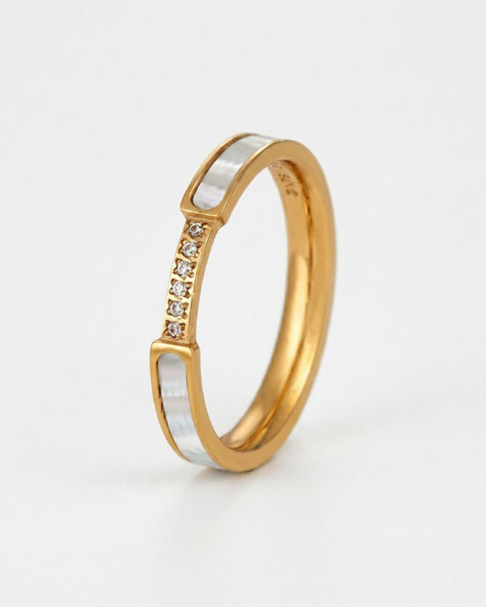 A gold band ring featuring a silver inlay with a row of small clear stones, photographed on a clean white background.