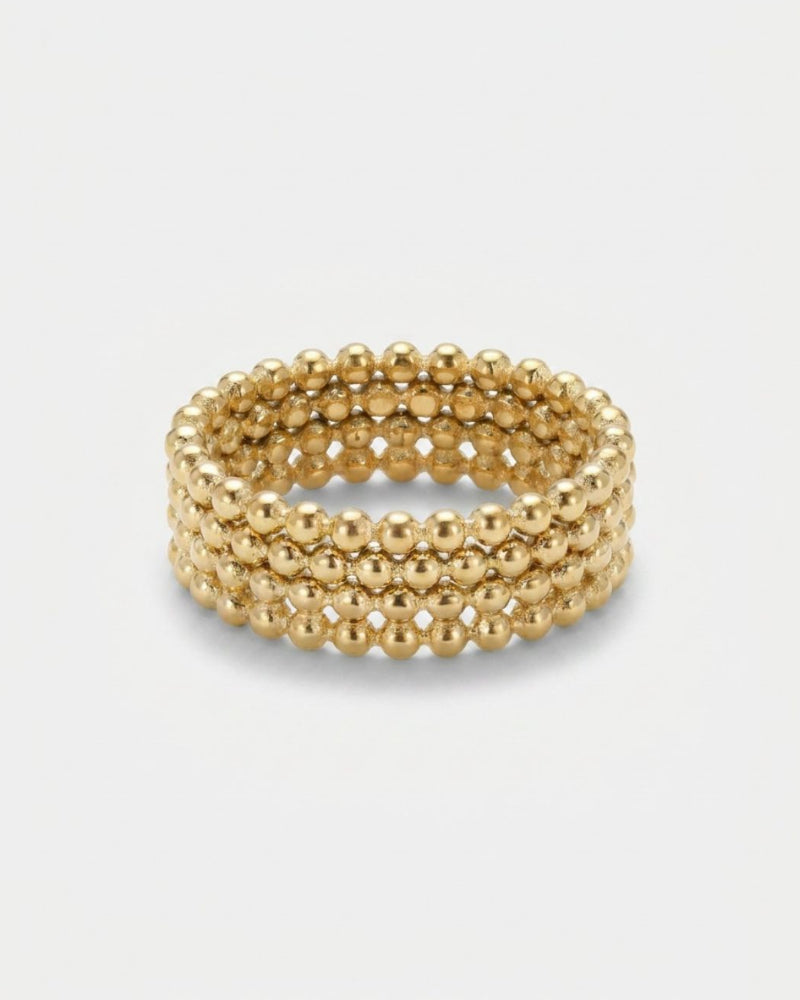 A gold beaded mesh ring with four rows of small metallic beads, photographed on a light gray background.