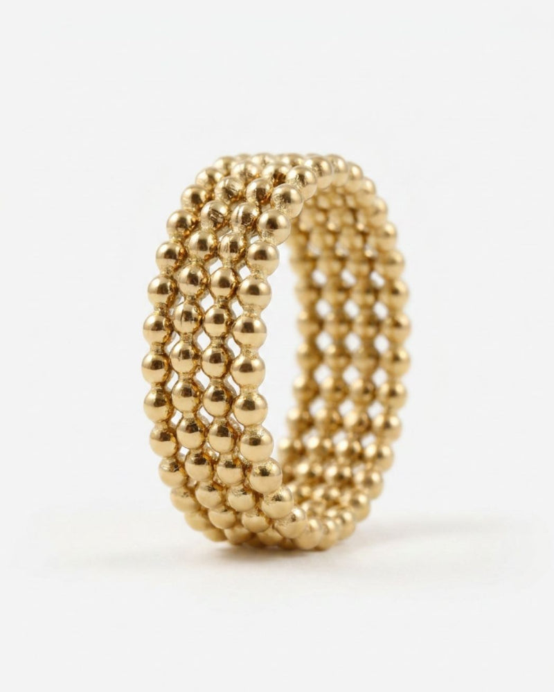 A gold-colored beaded ring with four rows of small metallic beads, photographed on a clean white background.