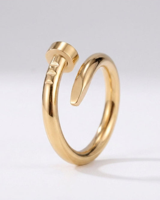 A polished gold-toned open ring with a sculptural, curved design and a textured top, displayed on a clean white background.