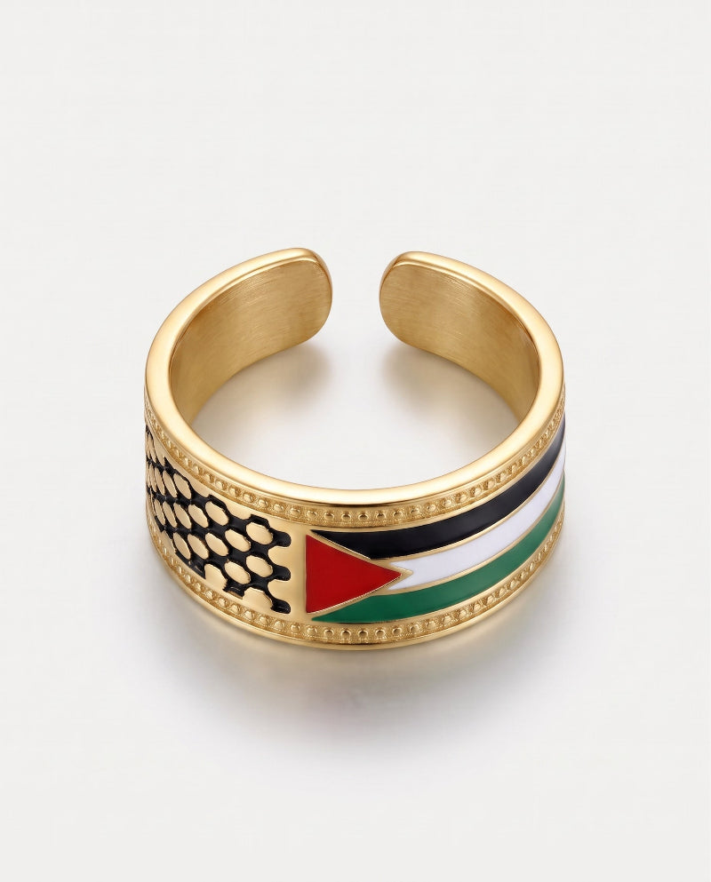 A gold-plated cuff ring featuring an inlaid design of the Palestinian flag, including black, white, green, and red enamel sections, set against a clean white background.