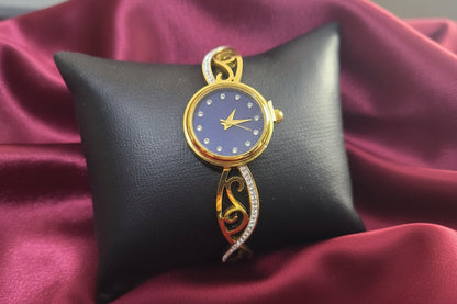 Gold watch on a black cushion with a red fabric background
