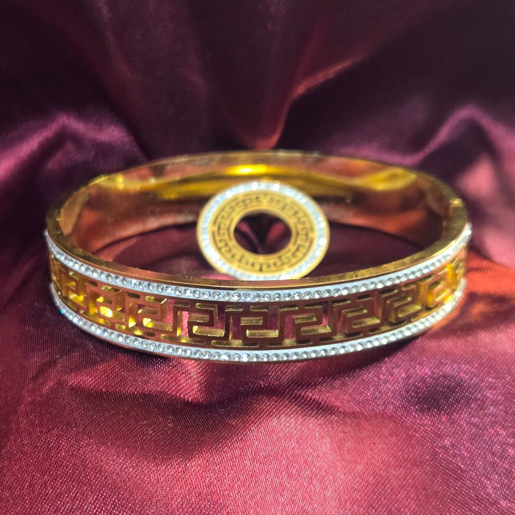 Gold bracelet with intricate designs on a red fabric background