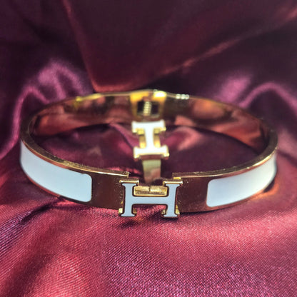 Gold bracelet with a logo on a purple fabric background