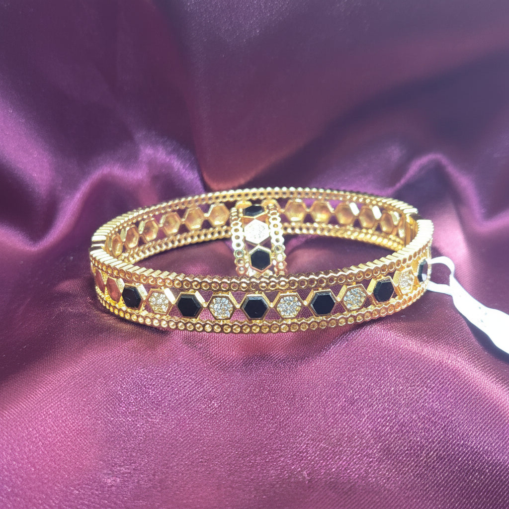 Gold bracelet with black stones on a purple fabric background