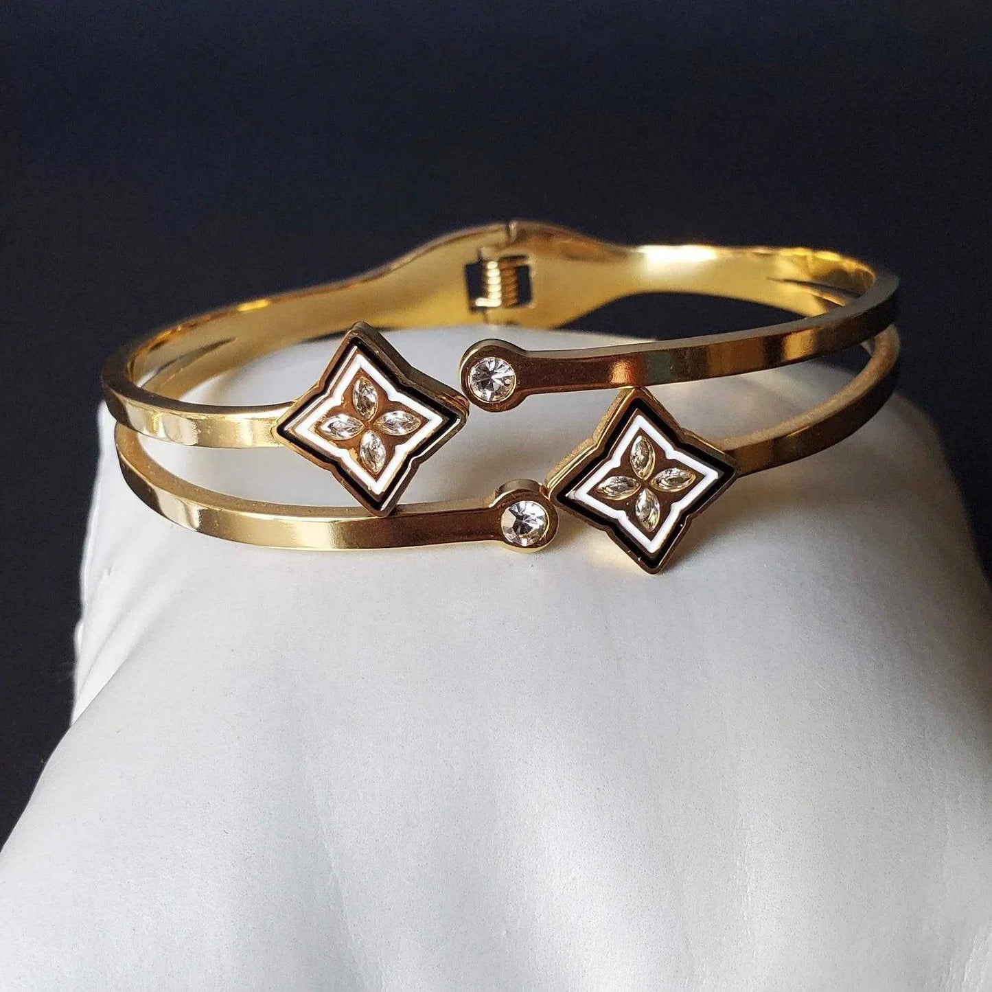 Gold bracelet with floral designs and crystals on a white surface