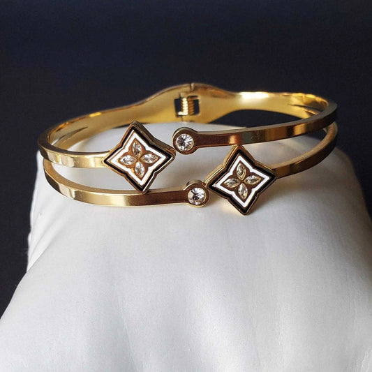 Gold bracelet with floral designs and crystals on a white surface