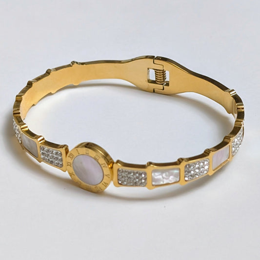 Gold bracelet with gemstone accents on a light gray background