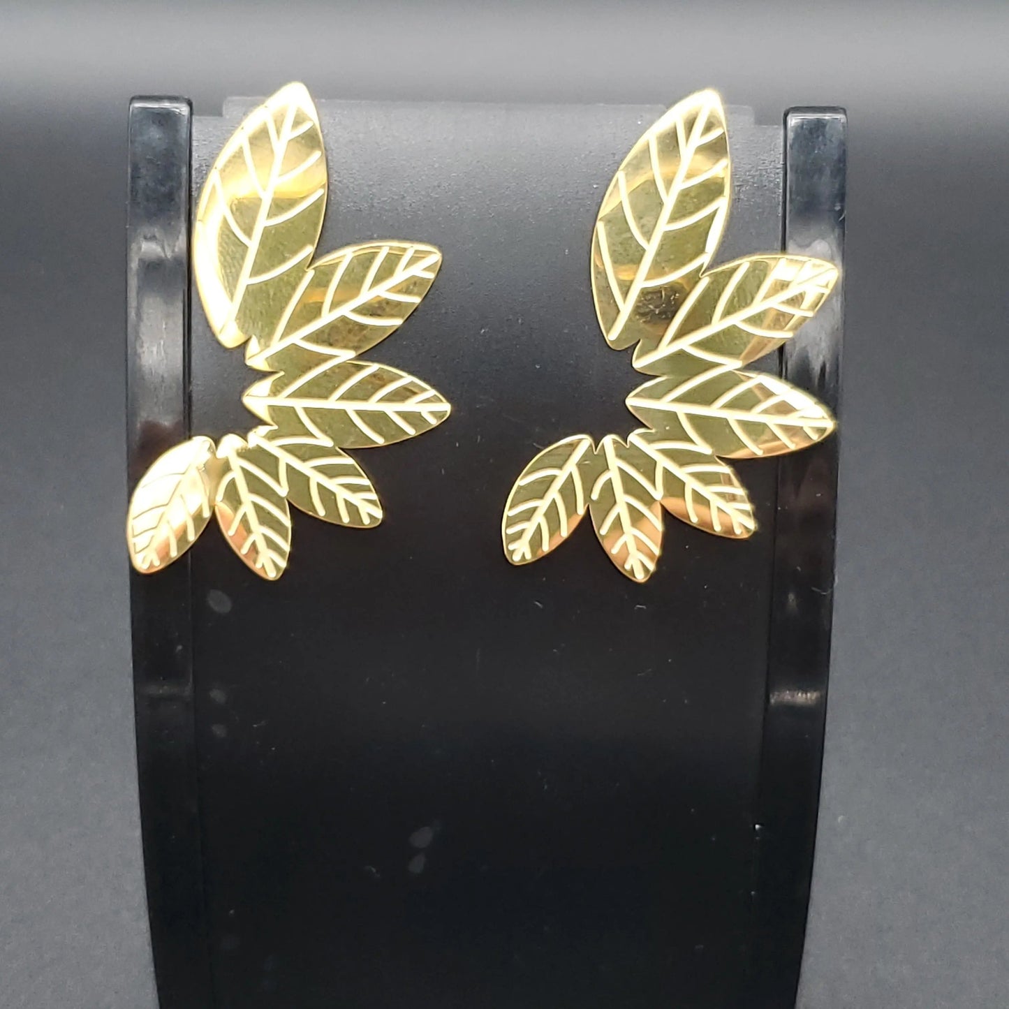 Gold leaf-shaped earrings with a red velvet fabric background