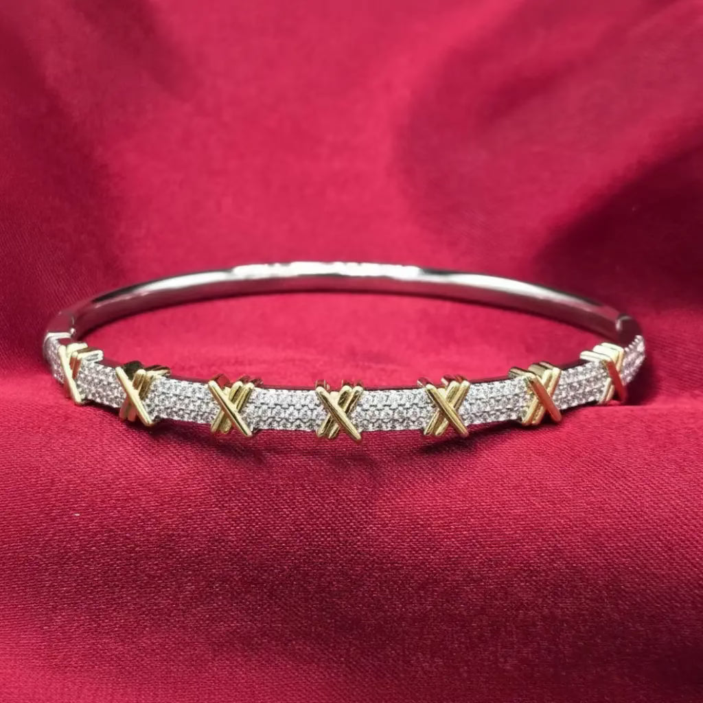 Golden Sixteen Stones Bangle by T*ffany on a red velvet fabric background