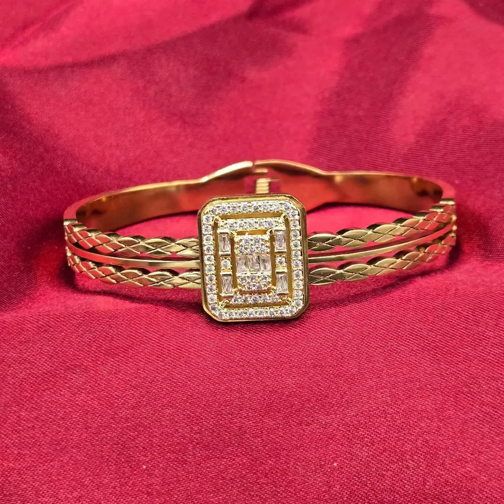 Golden Twist Bangle with zircon stones on a square shape on a red fabric background