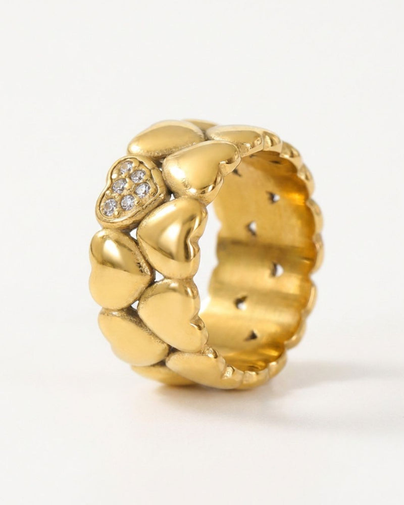 A gold heart-link ring with a central heart-shaped cluster of small clear stones, shown on a plain white background.