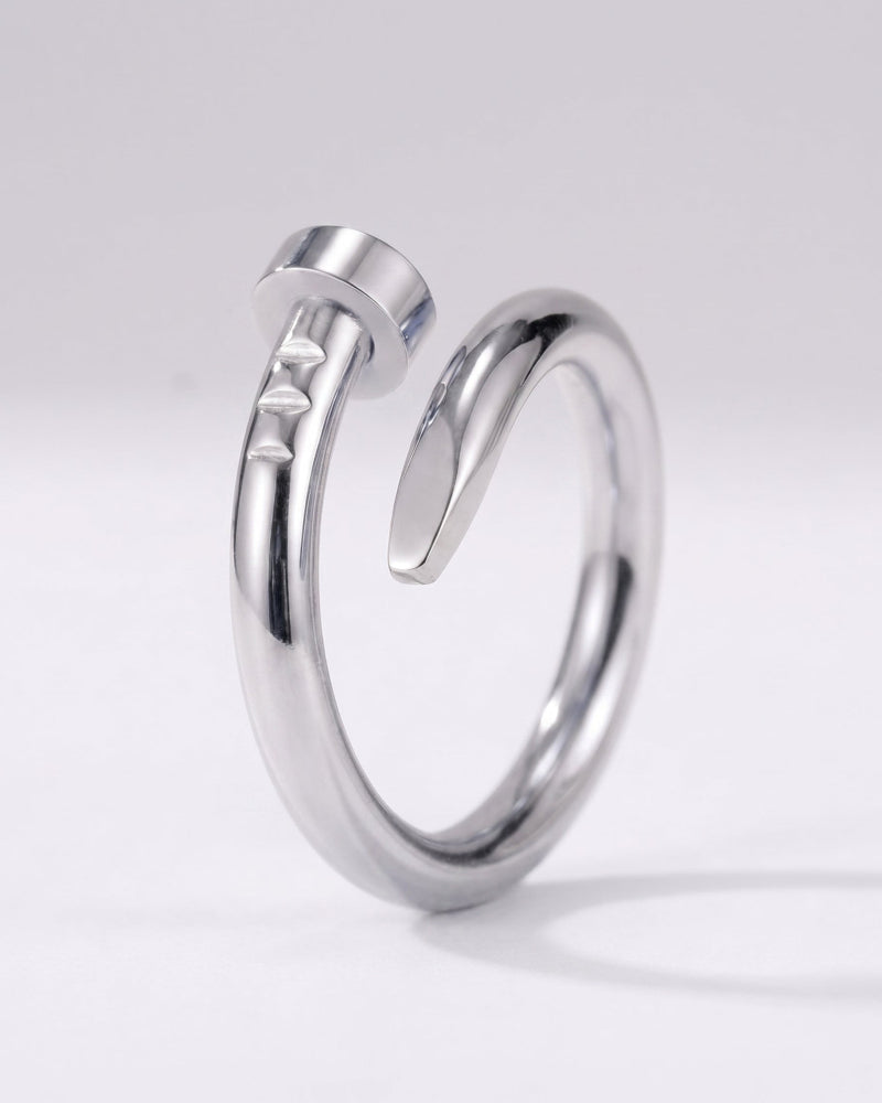 A polished silver-toned metal ring with a unique open design resembling a stylized hammer, photographed on a clean light gray background.