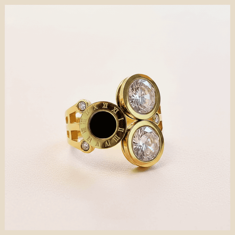Gold ring with black and clear gemstones on a white background