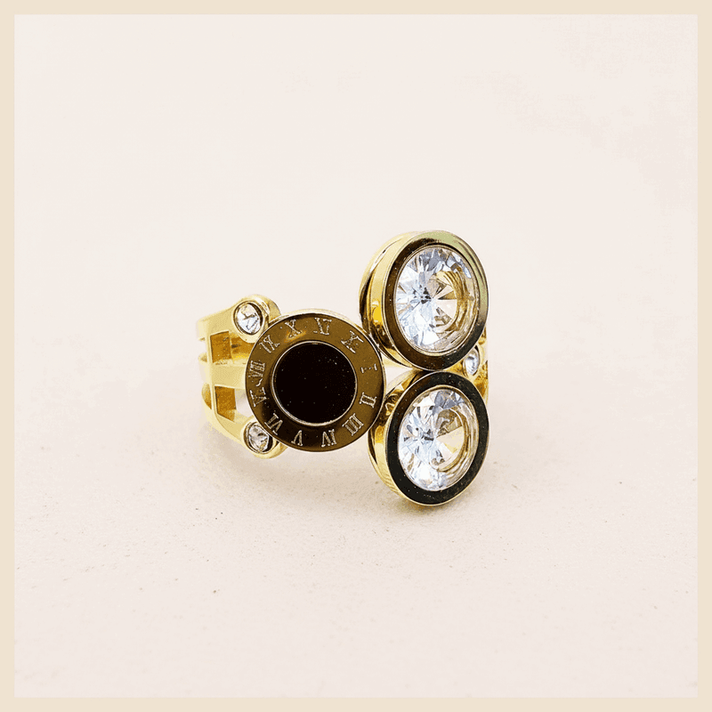 Gold ring with gemstones on a textured white surface