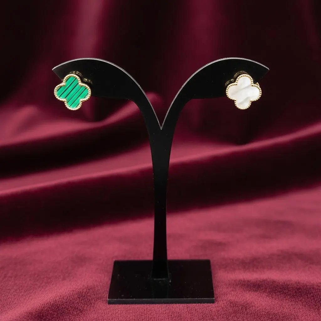 Pair of Van C*leef Double Face Earrings on a black display stand against a red velvet fabric background