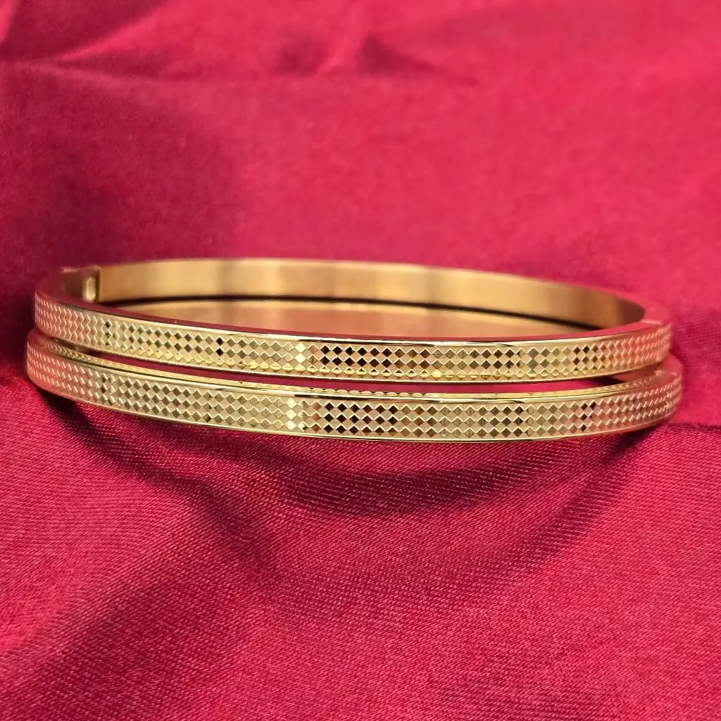 Two golden bangles with a checker design on a red fabric background