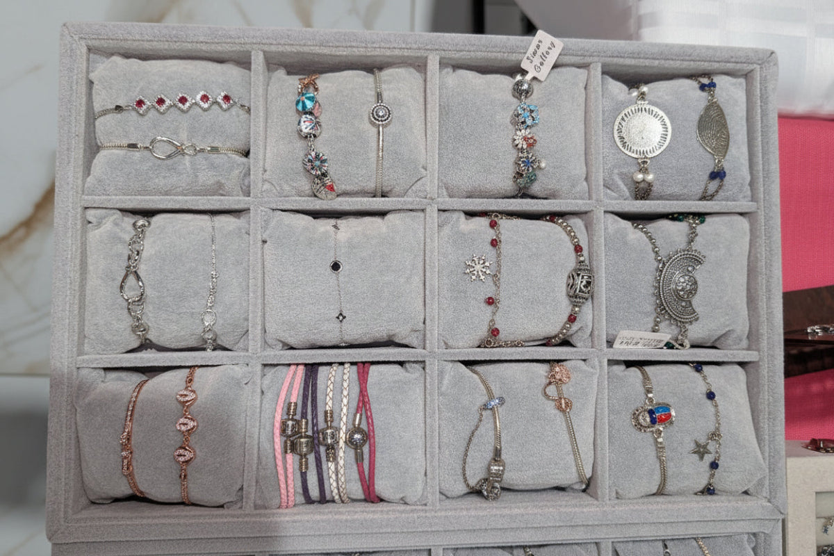 Gray jewelry display case with various bracelets on a marble surface