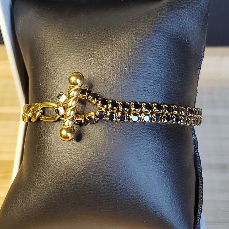 Gold and black bracelet on a black leather surface
