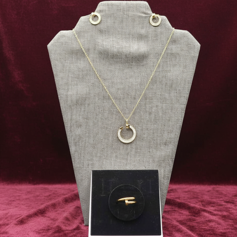 Gold necklace with a pendant on a gray fabric stand against a black background