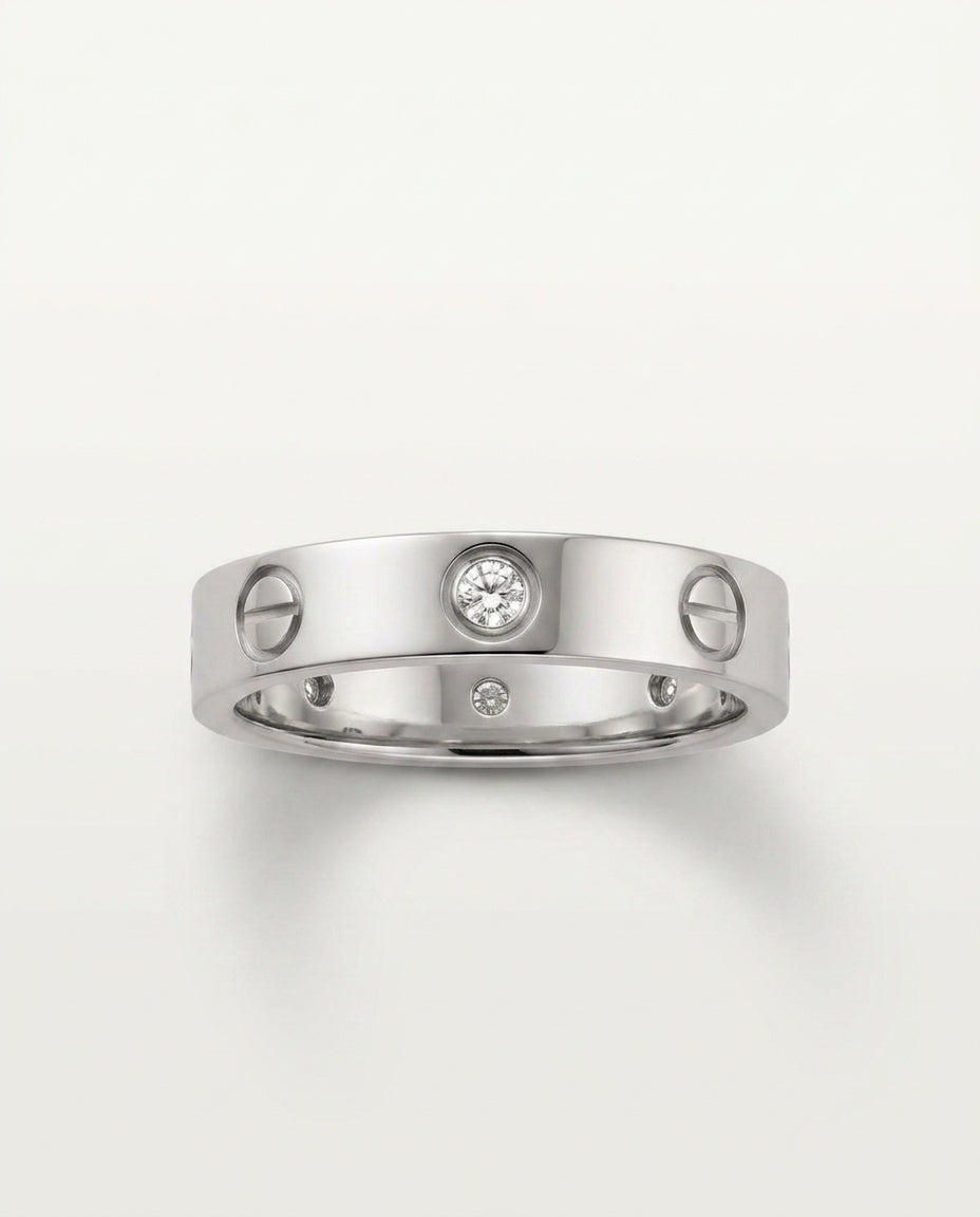 A silver-tone metal ring with a screw-head motif and a round clear gemstone in the center, photographed on a clean light background.