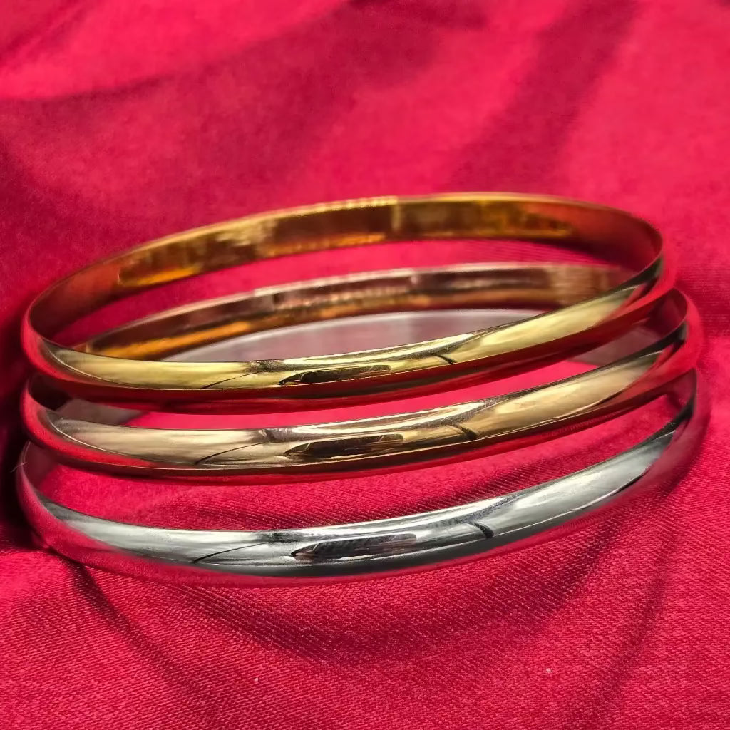 Three gold and silver bangles on a red fabric background