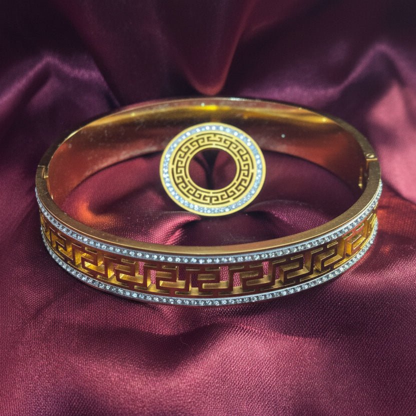 Gold bangle with intricate design on a purple satin background