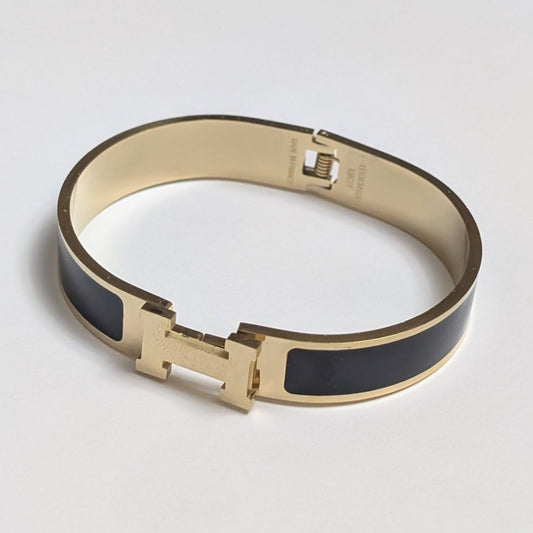 Gold and black bracelet on a light gray background
