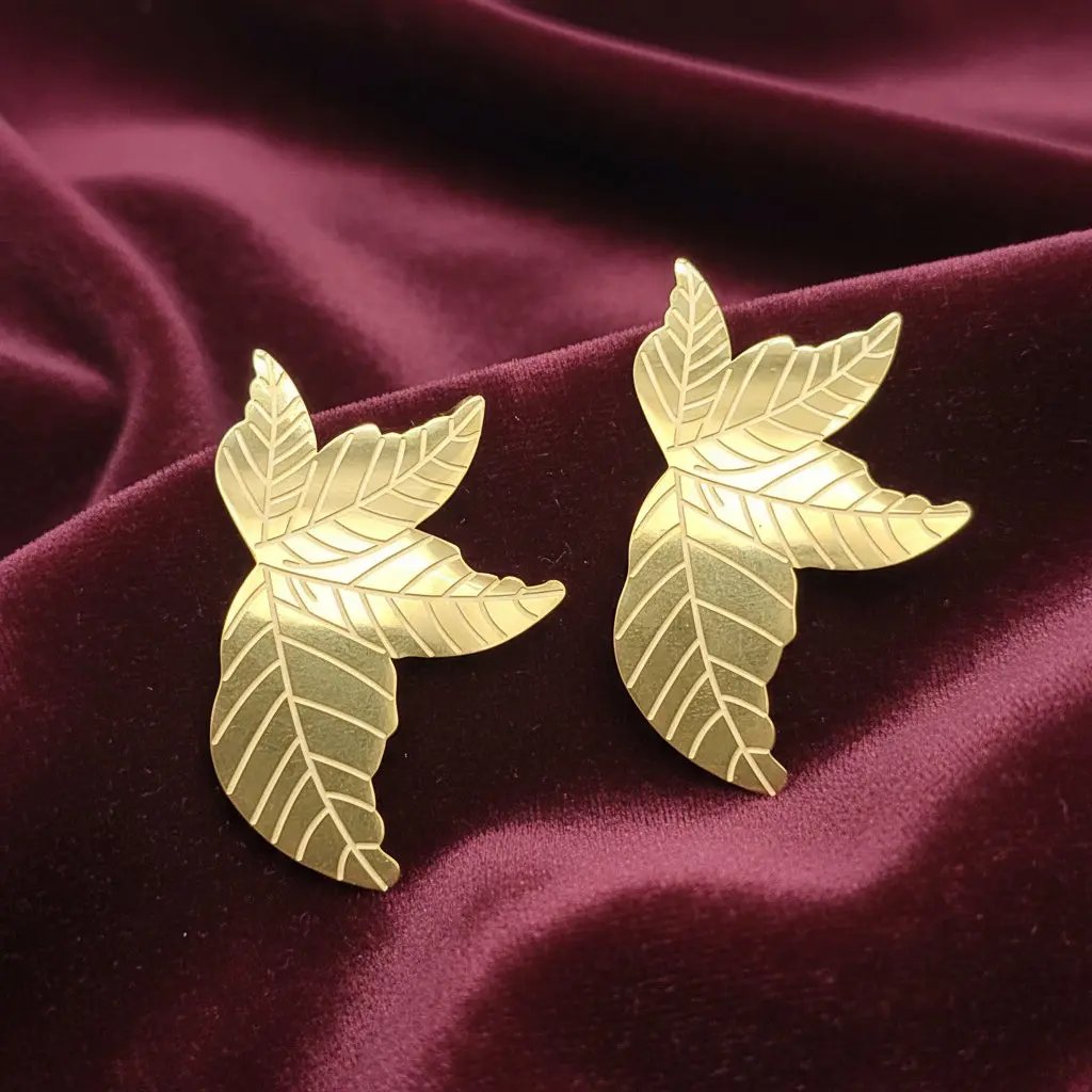 Gold leaf-shaped earrings with red velvet fabric background