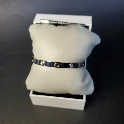 Love Screw Bangle in Silver finish, with cubic zirconia stone on a white pillow in a box