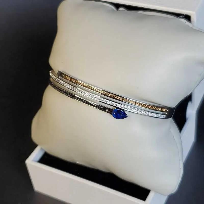 Modern Blue Teardrop Stone Bangle in Gold and Silver finish, with cubic zirconia stone on a neutral background