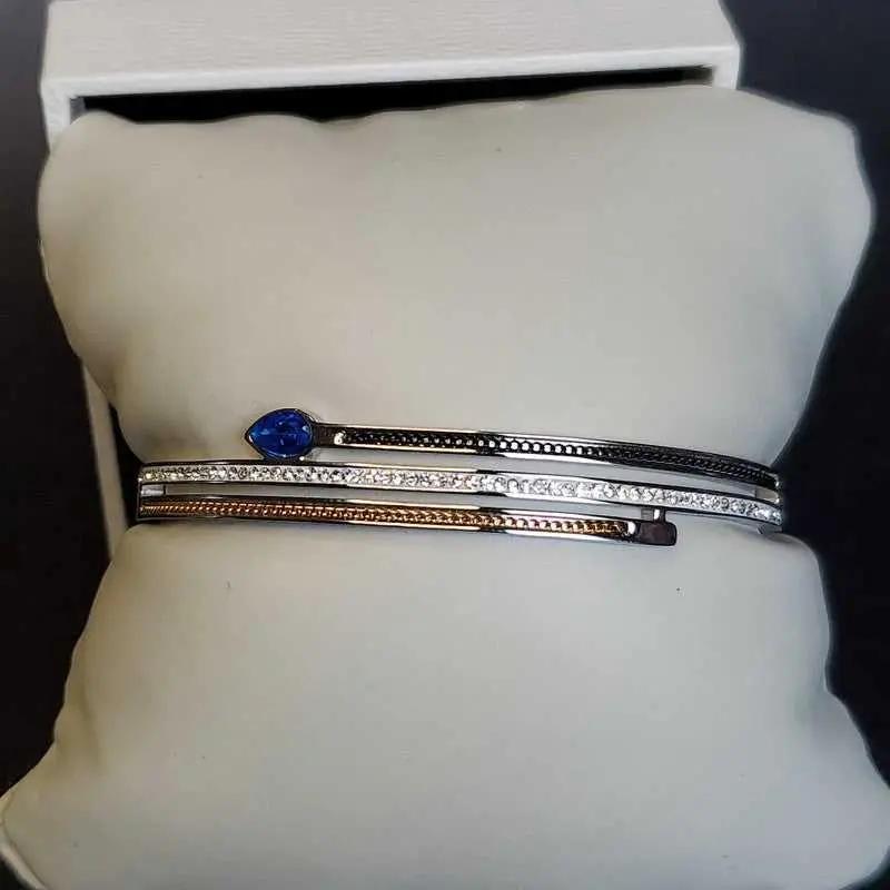 Modern Blue Teardrop Stone Bangle in Gold and Silver finish, with cubic zirconia stone on a neutral background