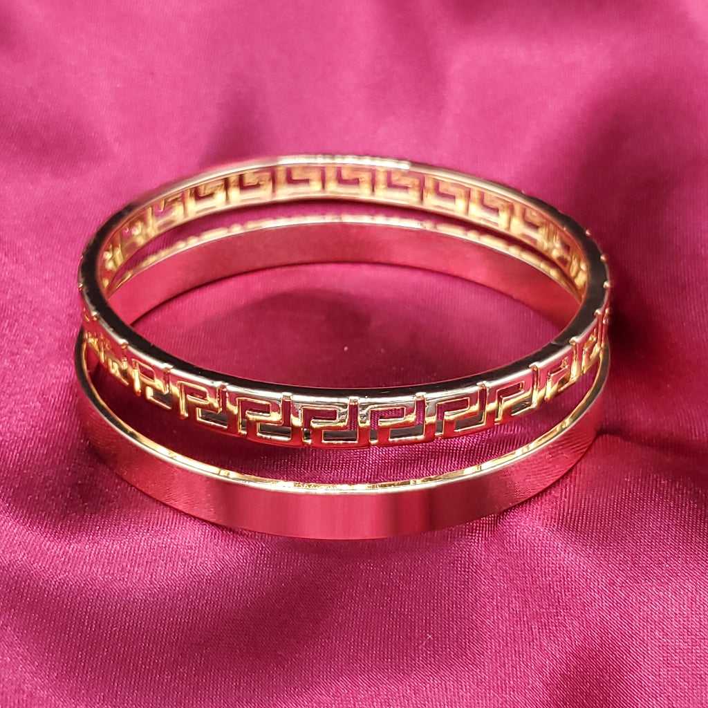 Modern Greek Key Bangle in Gold finish on a red fabric background