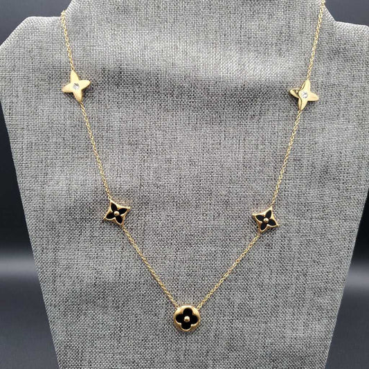 Monogram Flower Pendant Necklace in Gold finish, with cubic zirconia stone on a neutral background